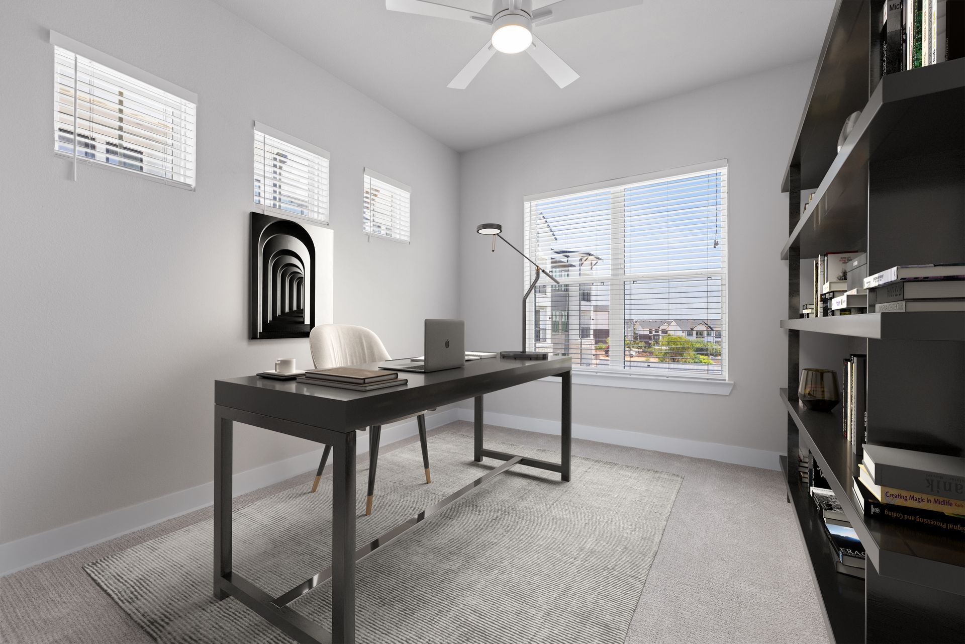 A home office with a desk, chair, bookshelf, and ceiling fan at The Wyatt, offers apartments in North Austin, TX, perfect for working from home.