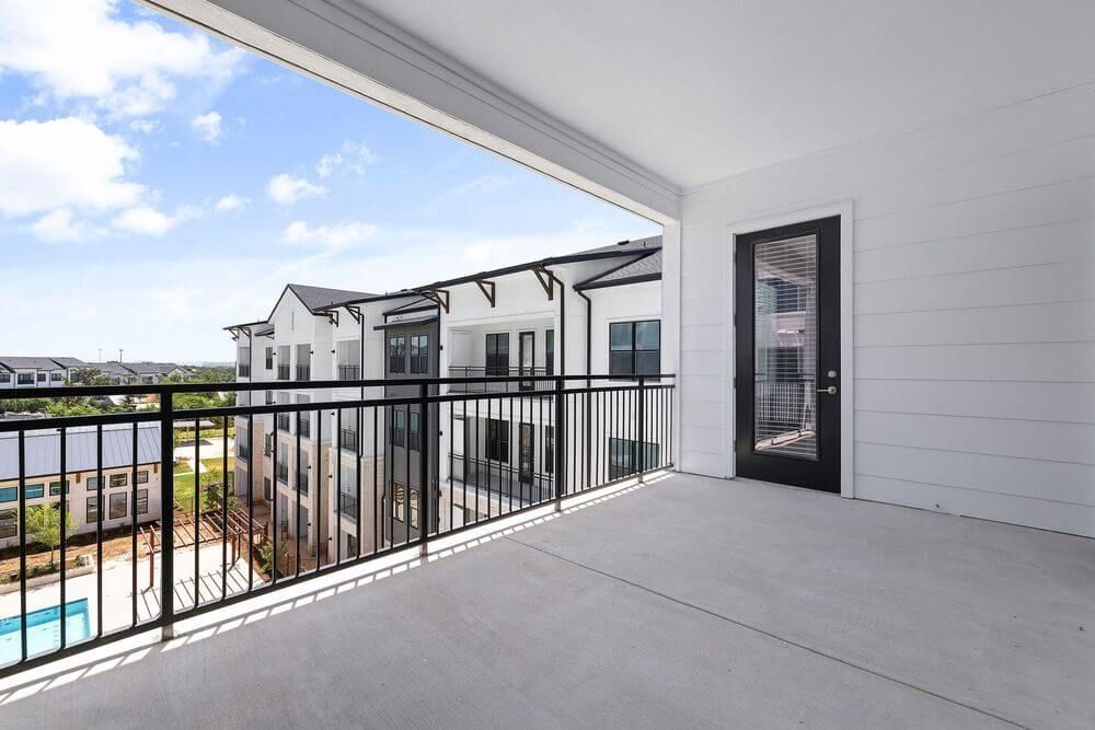 An empty balcony with a black railing and a door at The Wyatt, offers brand new apartments in North Austin, TX.
