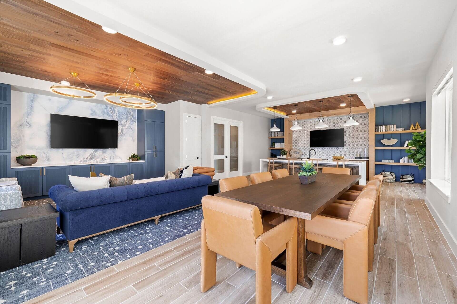 Apartment clubhouse with a blue couch, a table, chairs, and a television at The Wyatt, offers luxury apartments for rent in North Austin, TX.