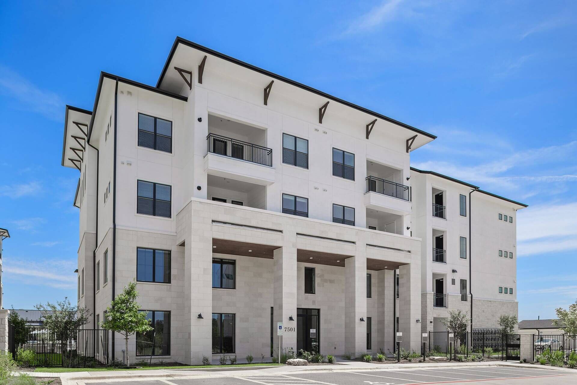 Exterior view of a large white apartment building with a lot of windows at The Wyatt, offers luxury Austin apartments.