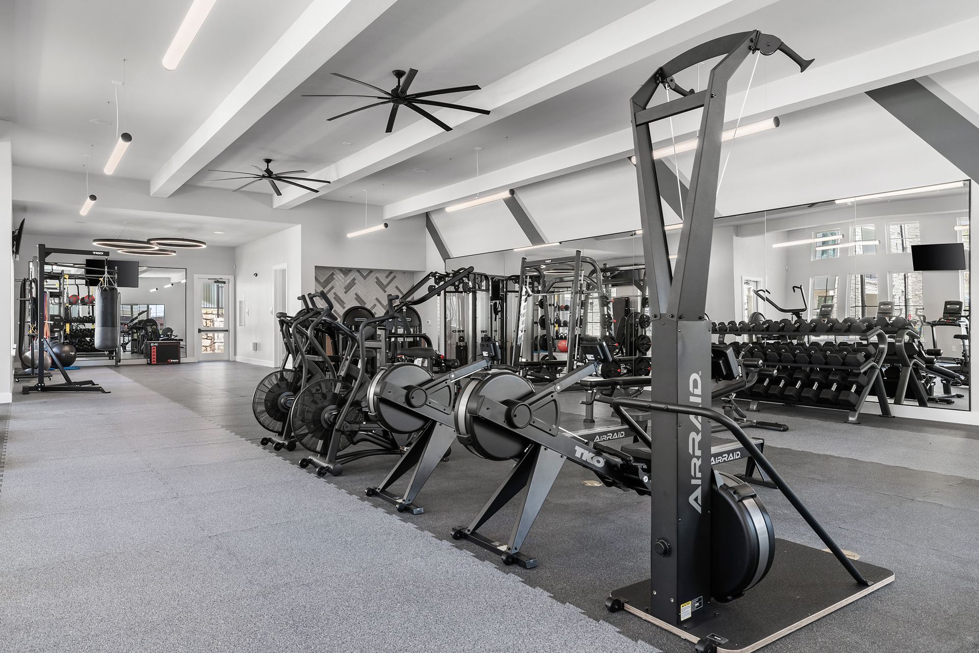 A large fitness center with a lot of equipment and a ceiling fan at The Wyatt, offers luxury apartments in North Austin, TX.