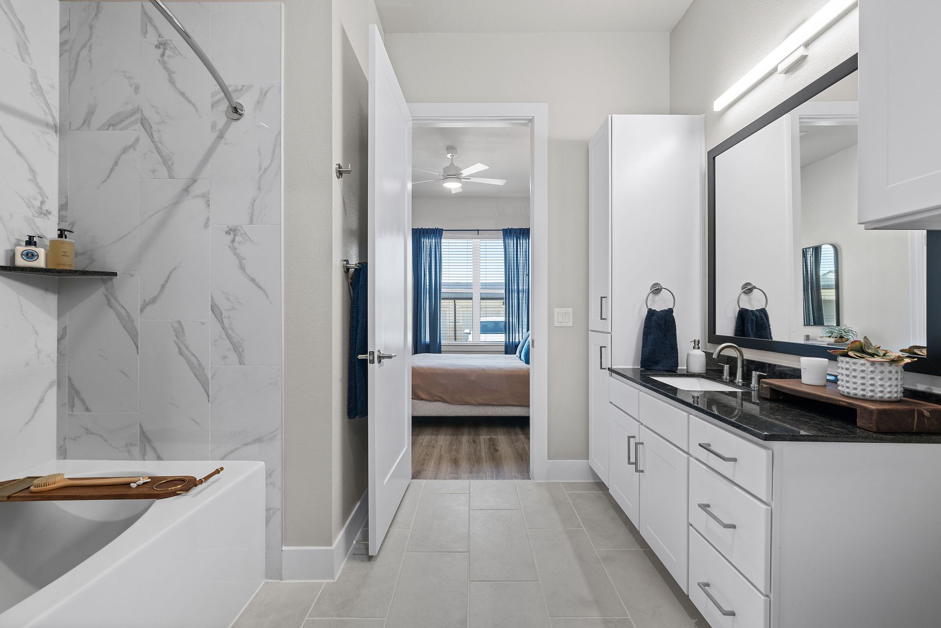 A bathroom with a bathtub, sink, mirror, and walk-in shower with marble. backsplash at The Wyatt, offers luxury apartments in North Austin, TX.