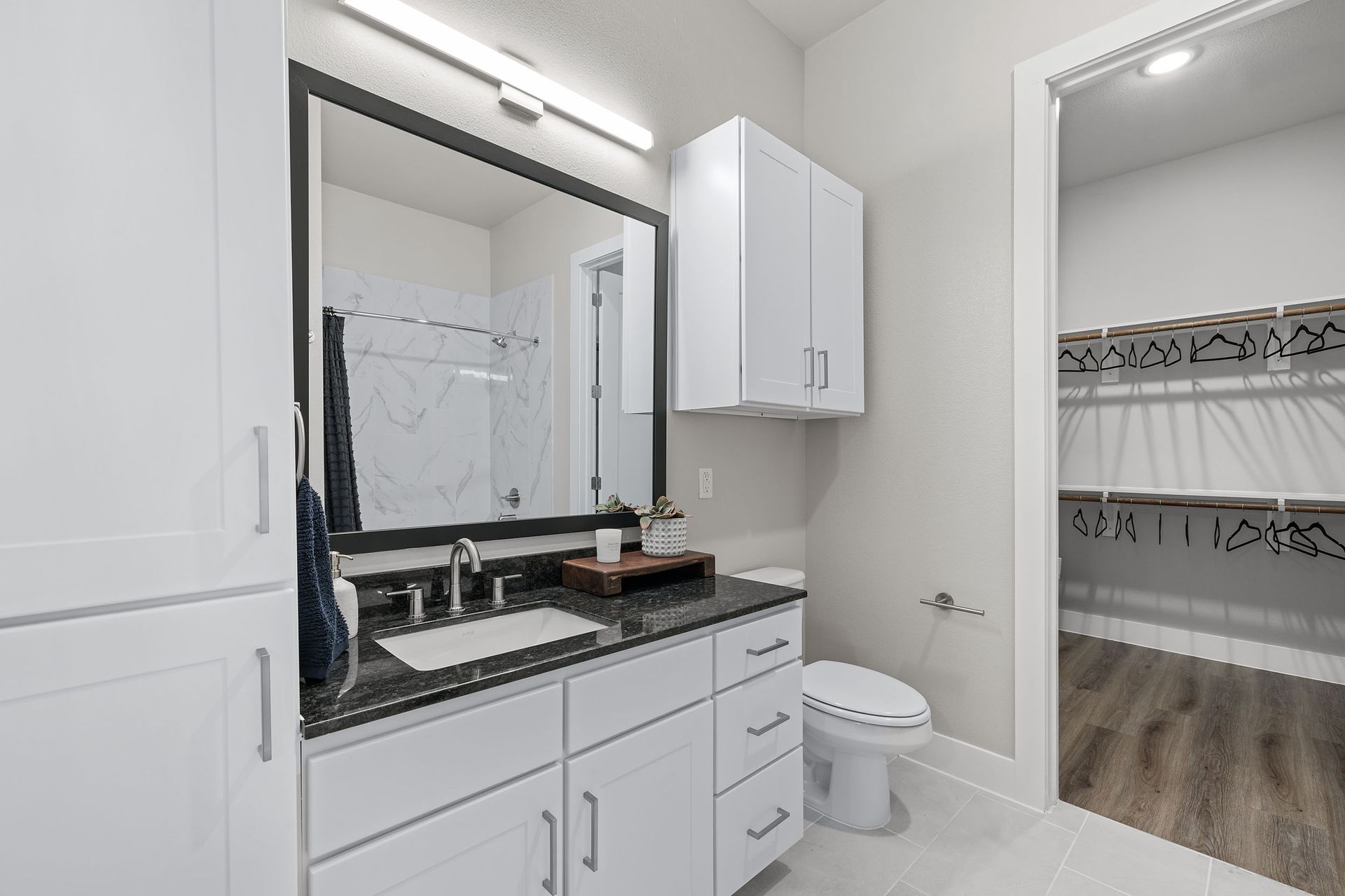 A bathroom with a sink, toilet, mirror, 
 and closet at The Wyatt, offers luxury apartments in North Austin, TX.