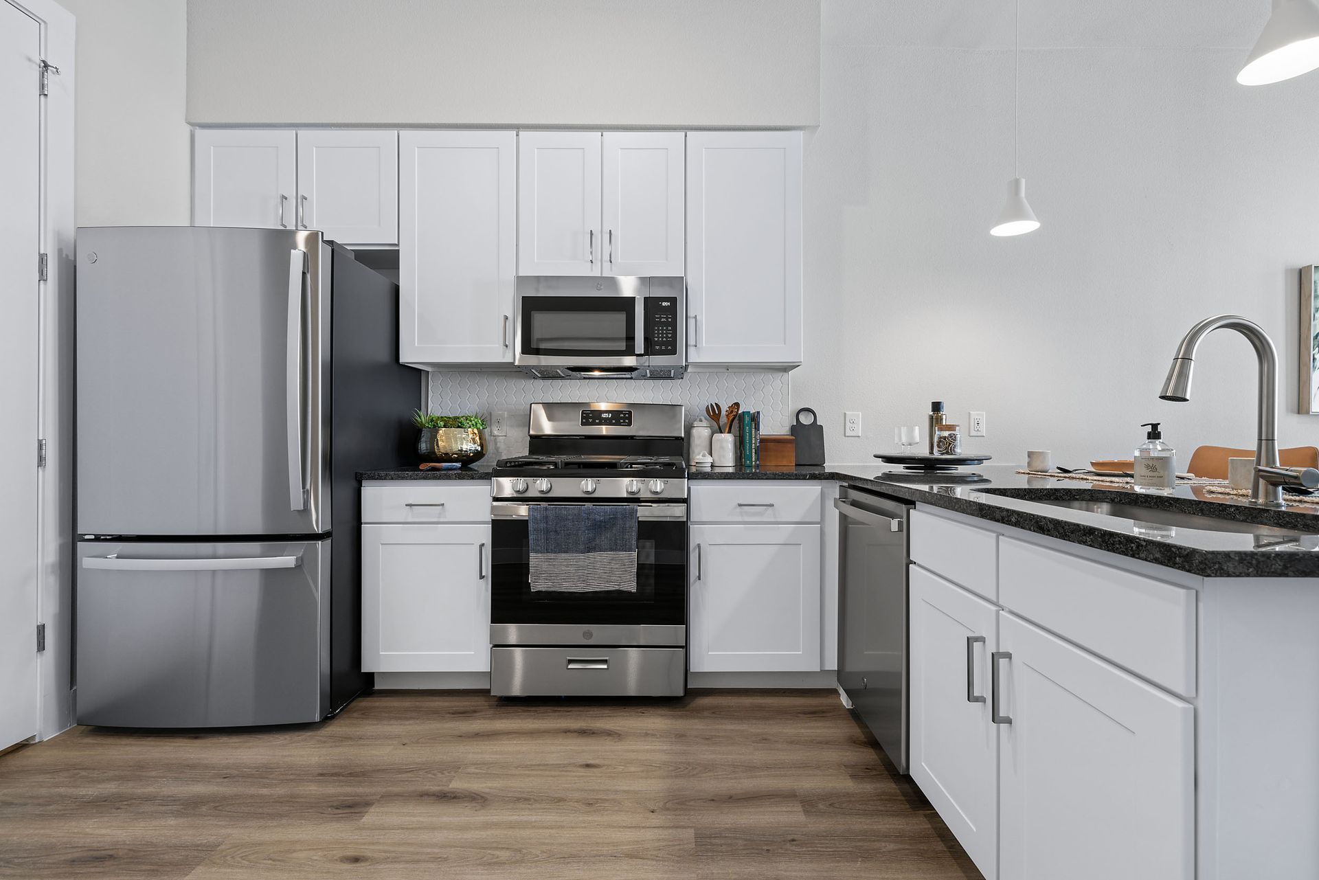 A kitchen with stainless steel appliances, white cabinets, and a large sink at The Wyatt, offers luxury apartments in North Austin, TX.