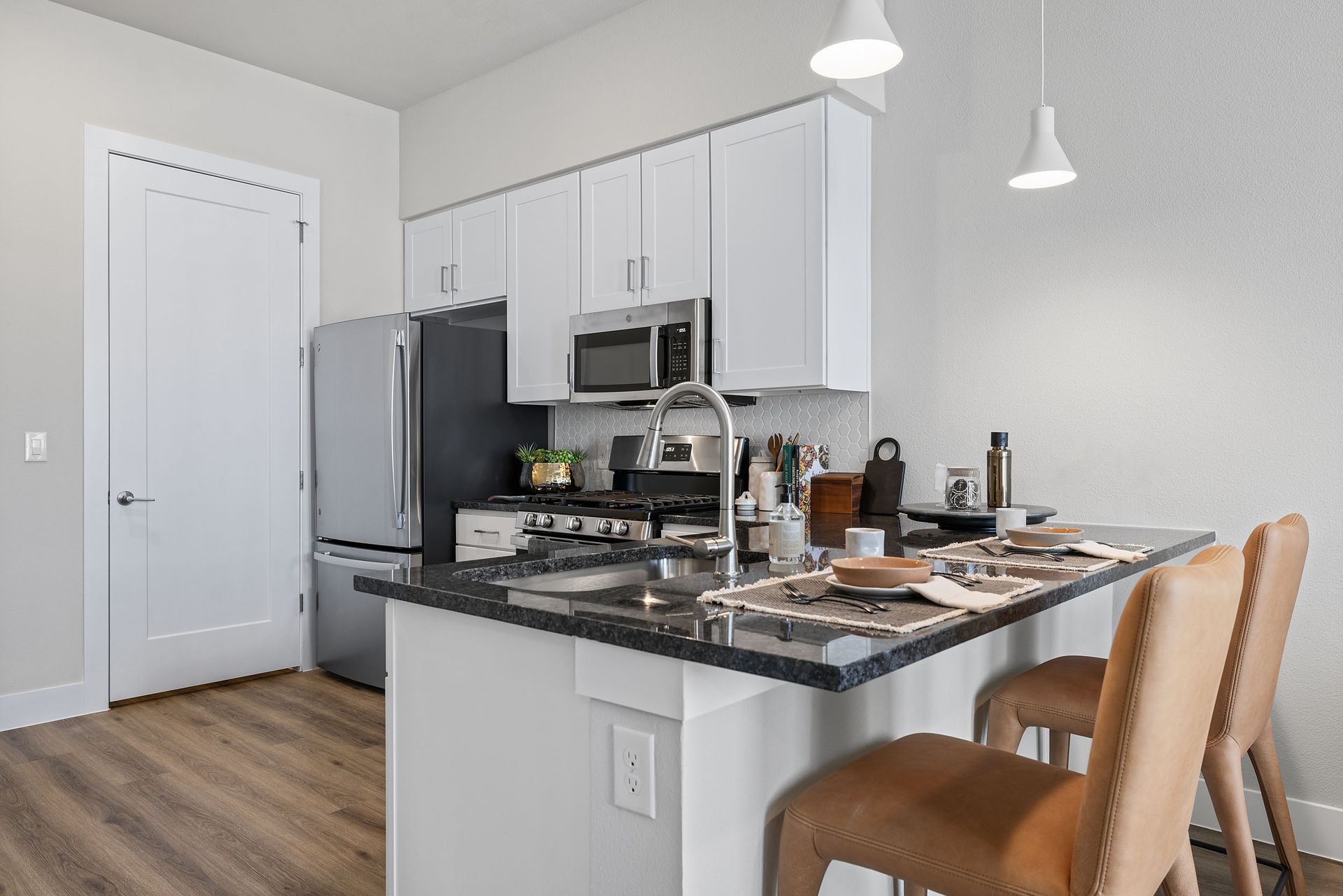 Apartment kitchen with white cabinets, spacious kitchen island, and bar seating at The Wyatt, offers luxury apartments in North Austin, TX.