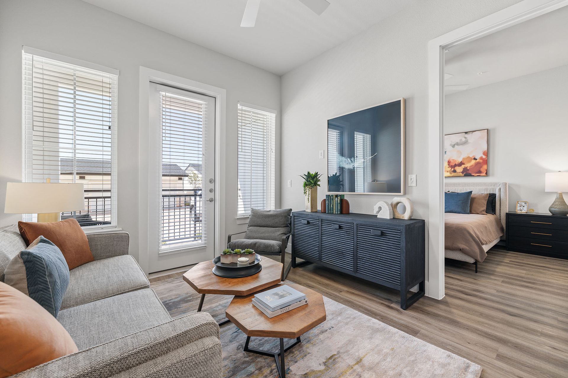 A living room with a couch, chairs, coffee tables, a television, and exist to a balcony at The Wyatt, offers Pearson Ranch apartments in Austin.