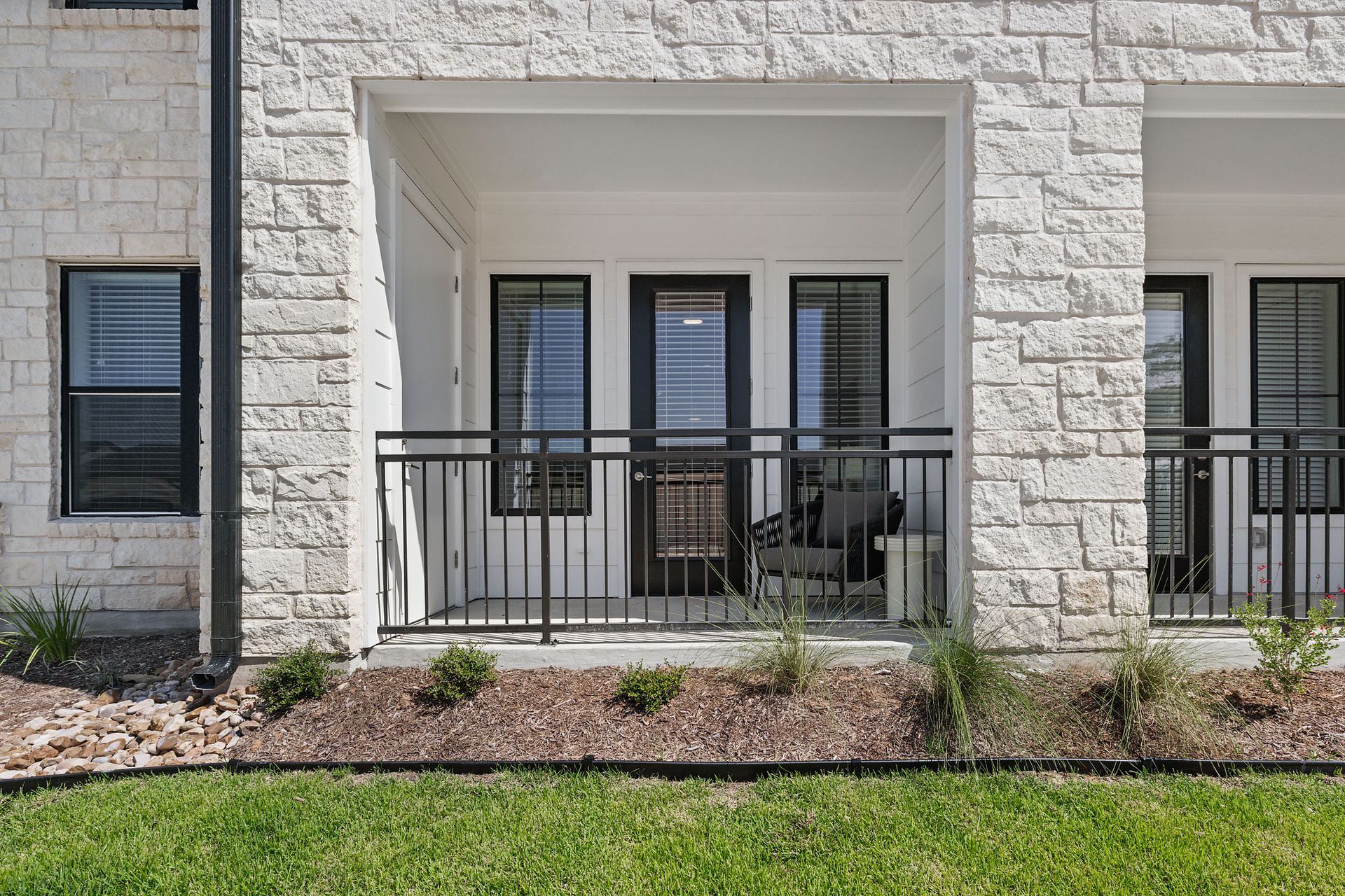 A brick building with a balcony and a lawn in front of it at The Wyatt, offers luxury apartments in North Austin, TX.