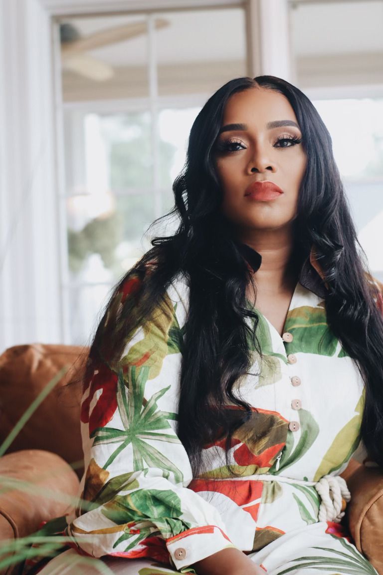 A woman in a floral dress is sitting on a couch.