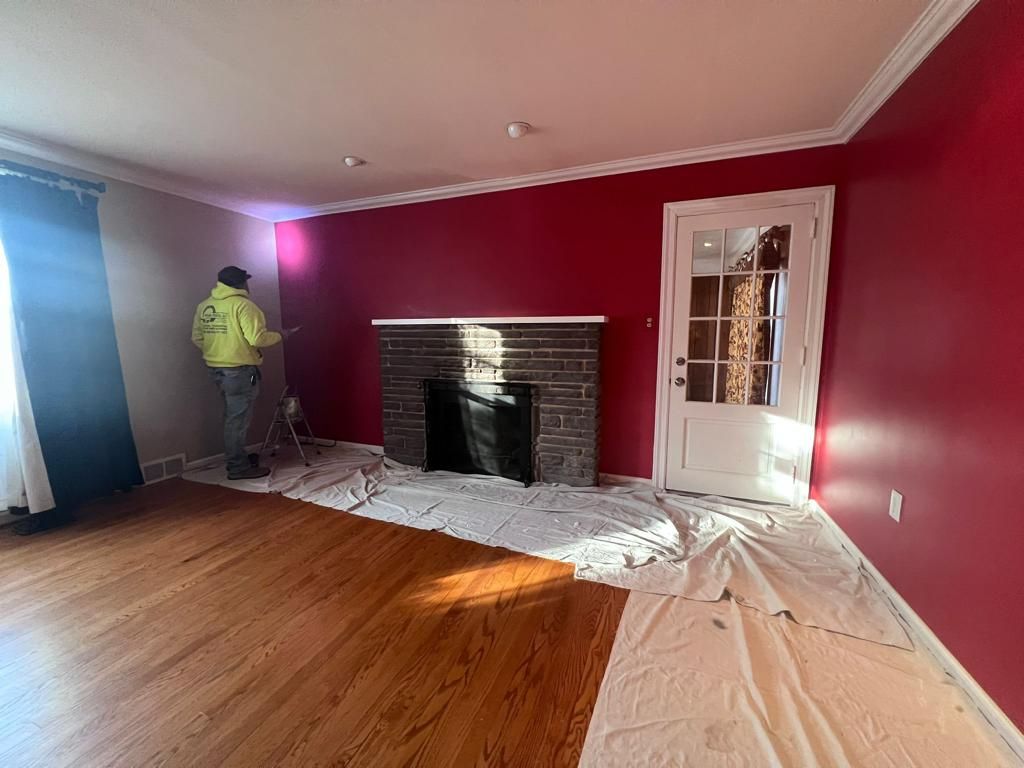 A man is standing in a living room with red walls and a fireplace.