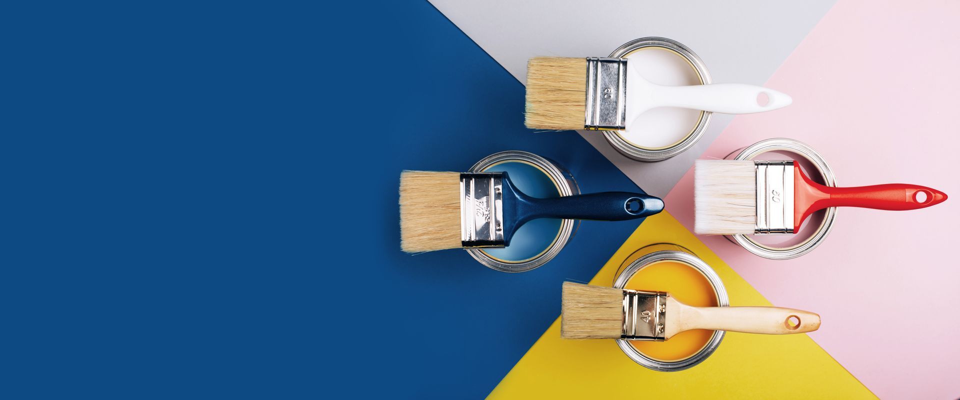 Three paint brushes are sitting on top of three cans of paint.