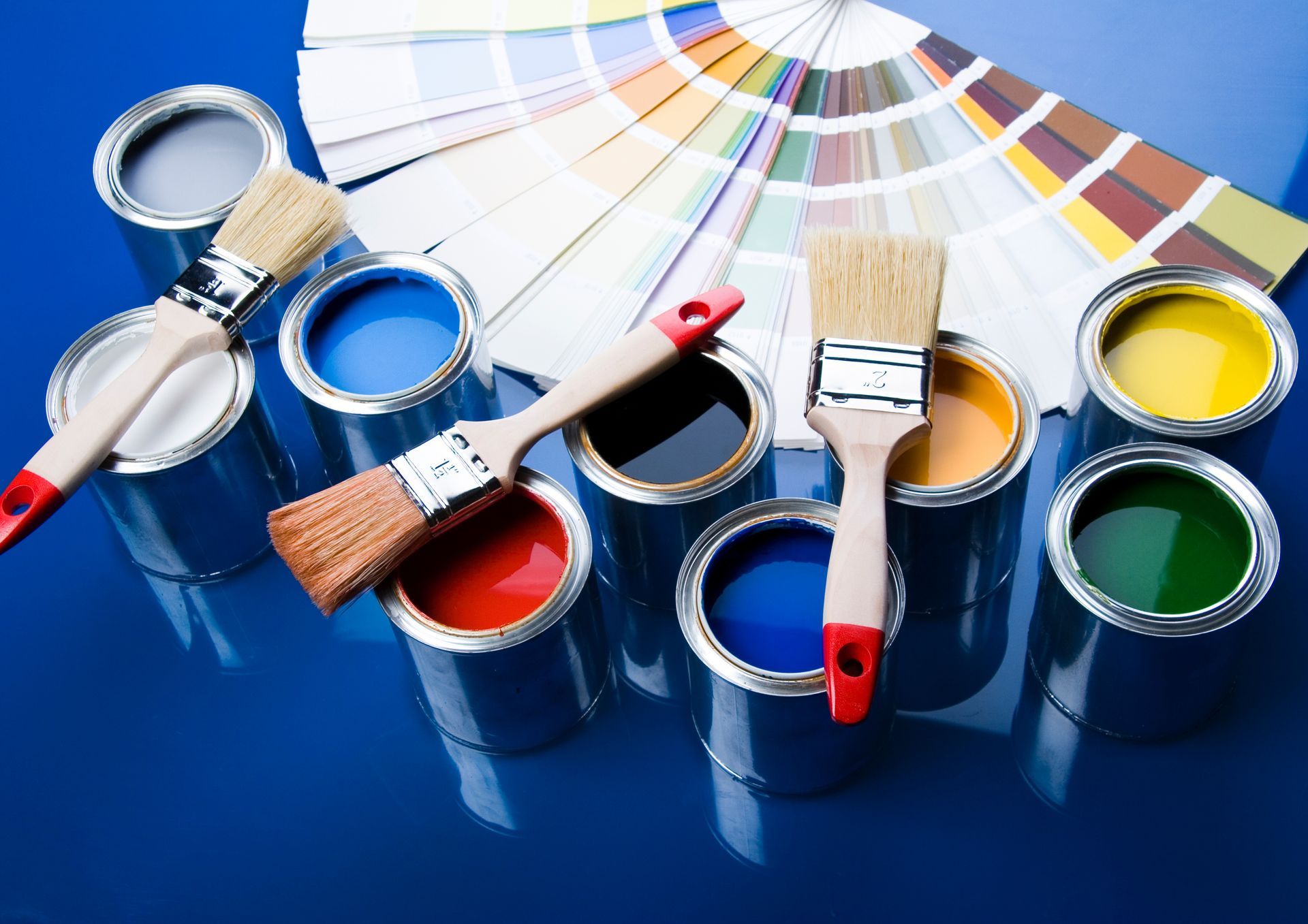 Cans of paint and brushes on a blue surface