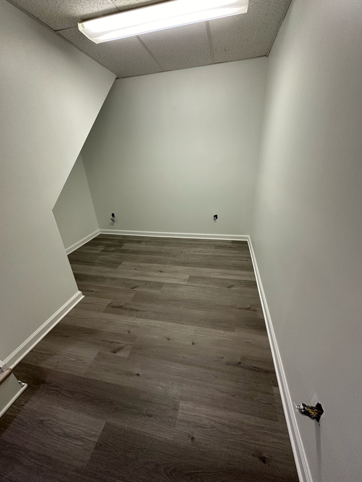 An empty room with hardwood floors and white walls.