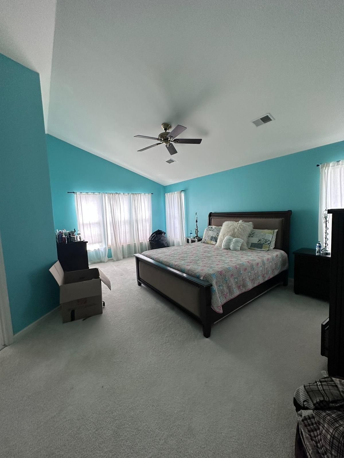 A bedroom with blue walls and a ceiling fan.