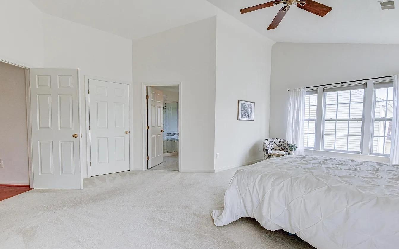 There is a ceiling fan in the bedroom with a large bed.