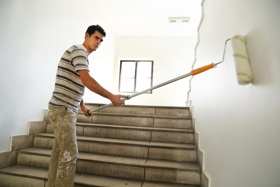 A man is painting a wall with a roller