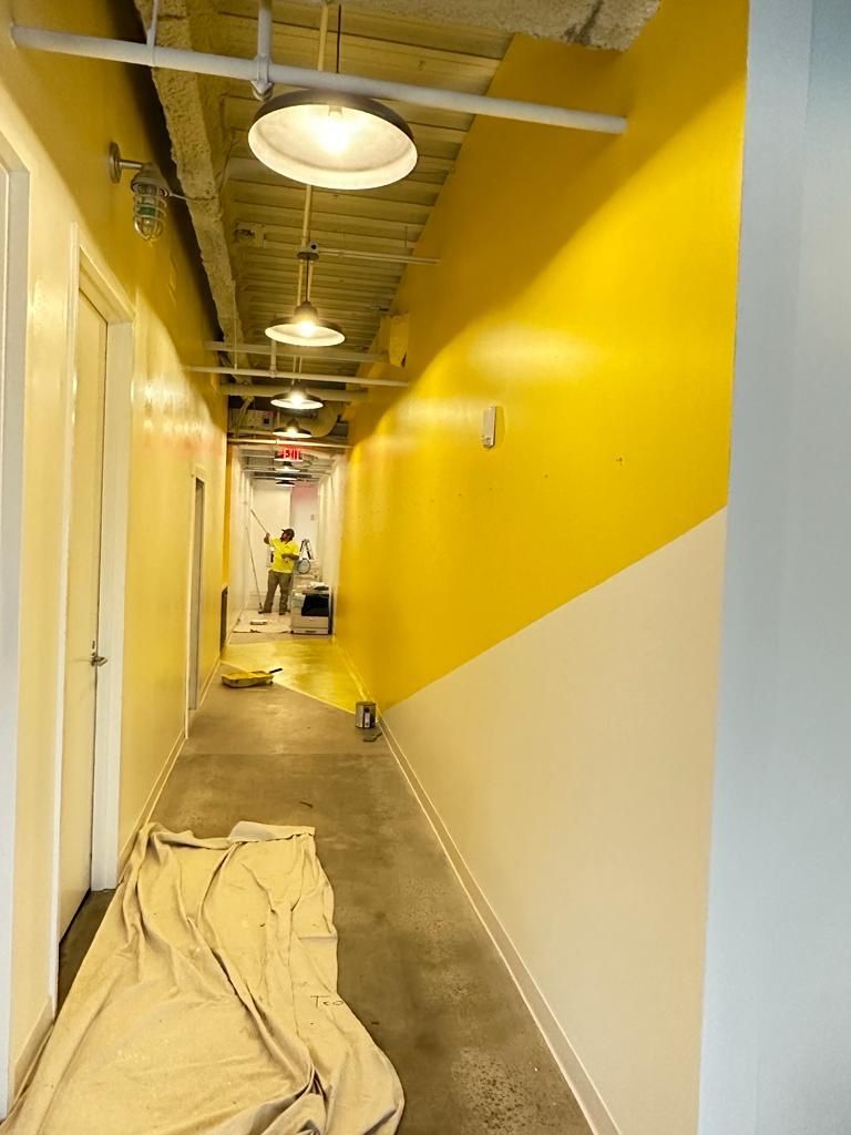 A hallway with yellow and white walls is being painted.