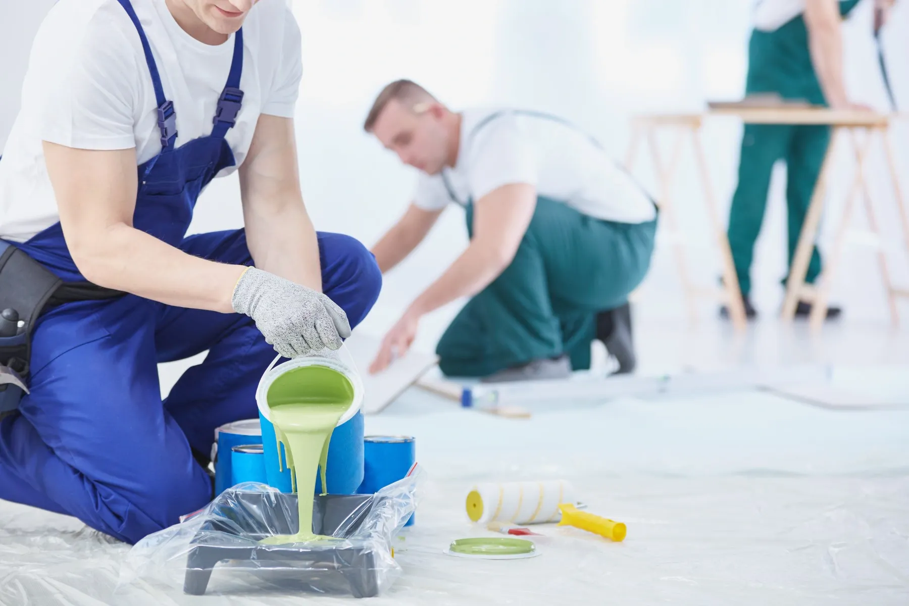 A man is pouring green paint into a tray.