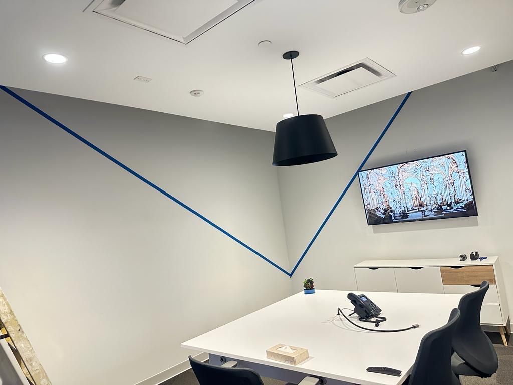 A conference room with a table and chairs and a television on the wall.