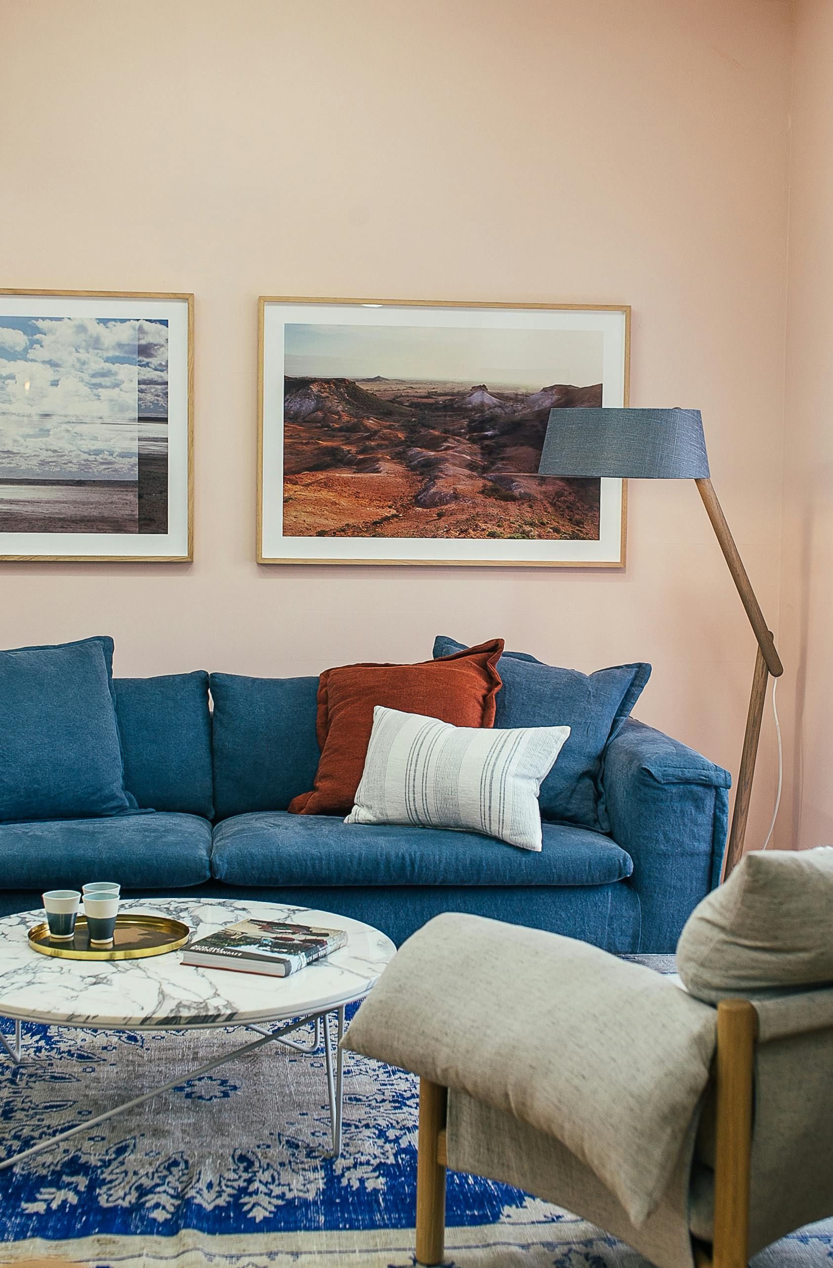 A living room with a blue couch , chair , coffee table and lamp.