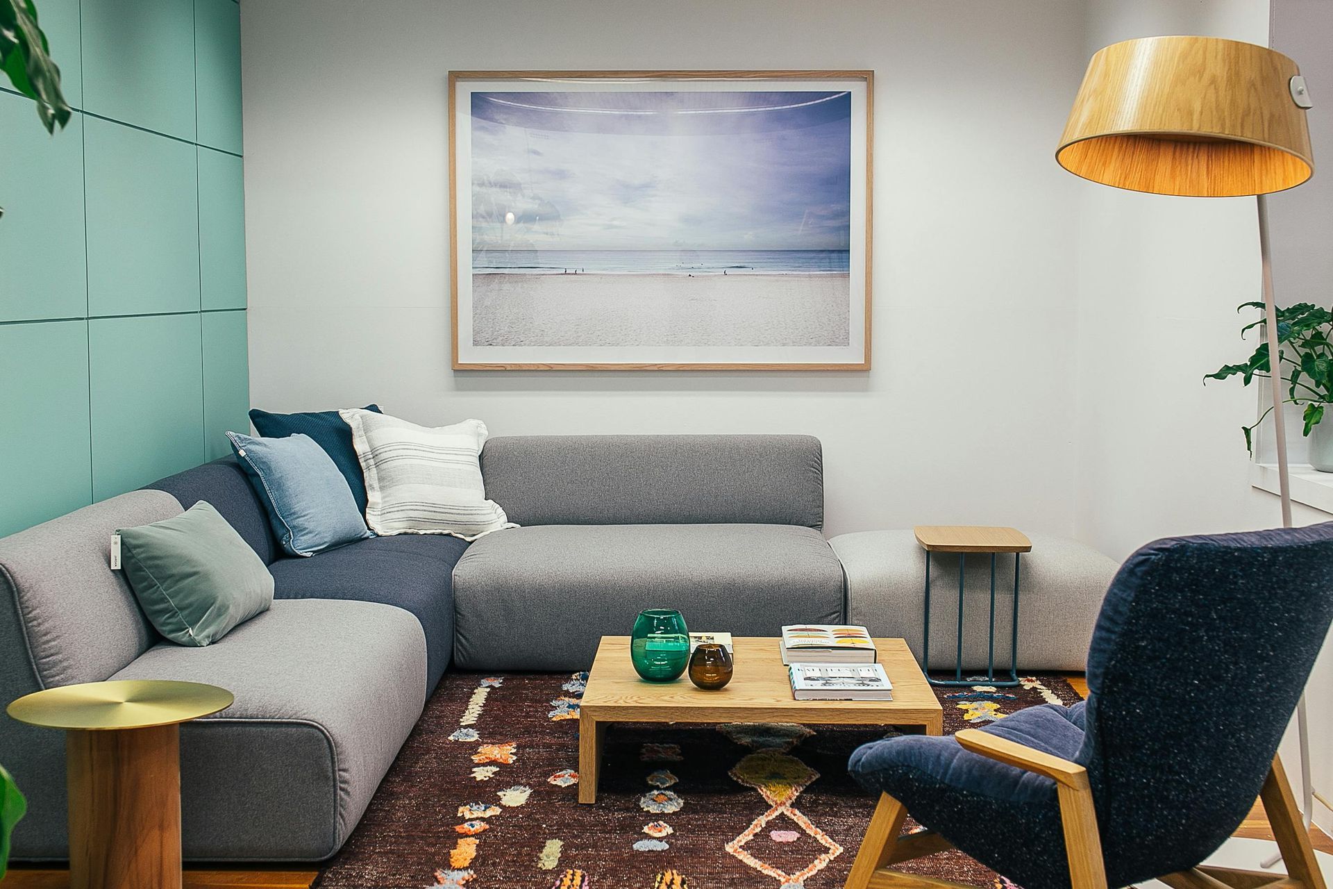 A living room with a couch , chair , coffee table and painting on the wall.