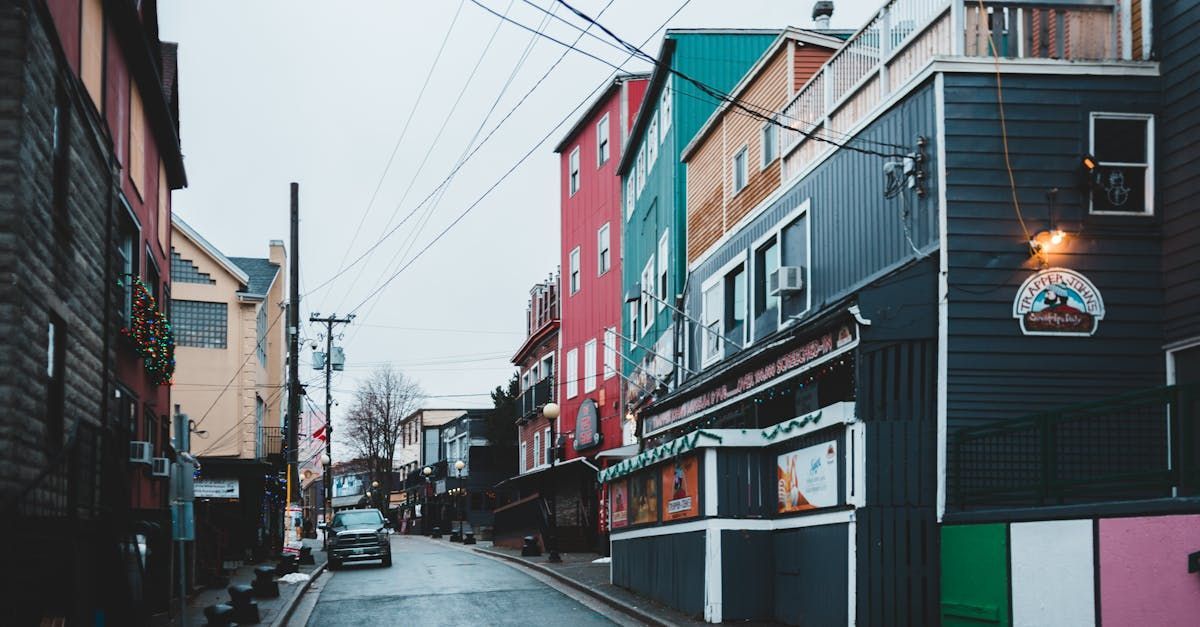 A street with a lot of buildings on it and a car driving down it.