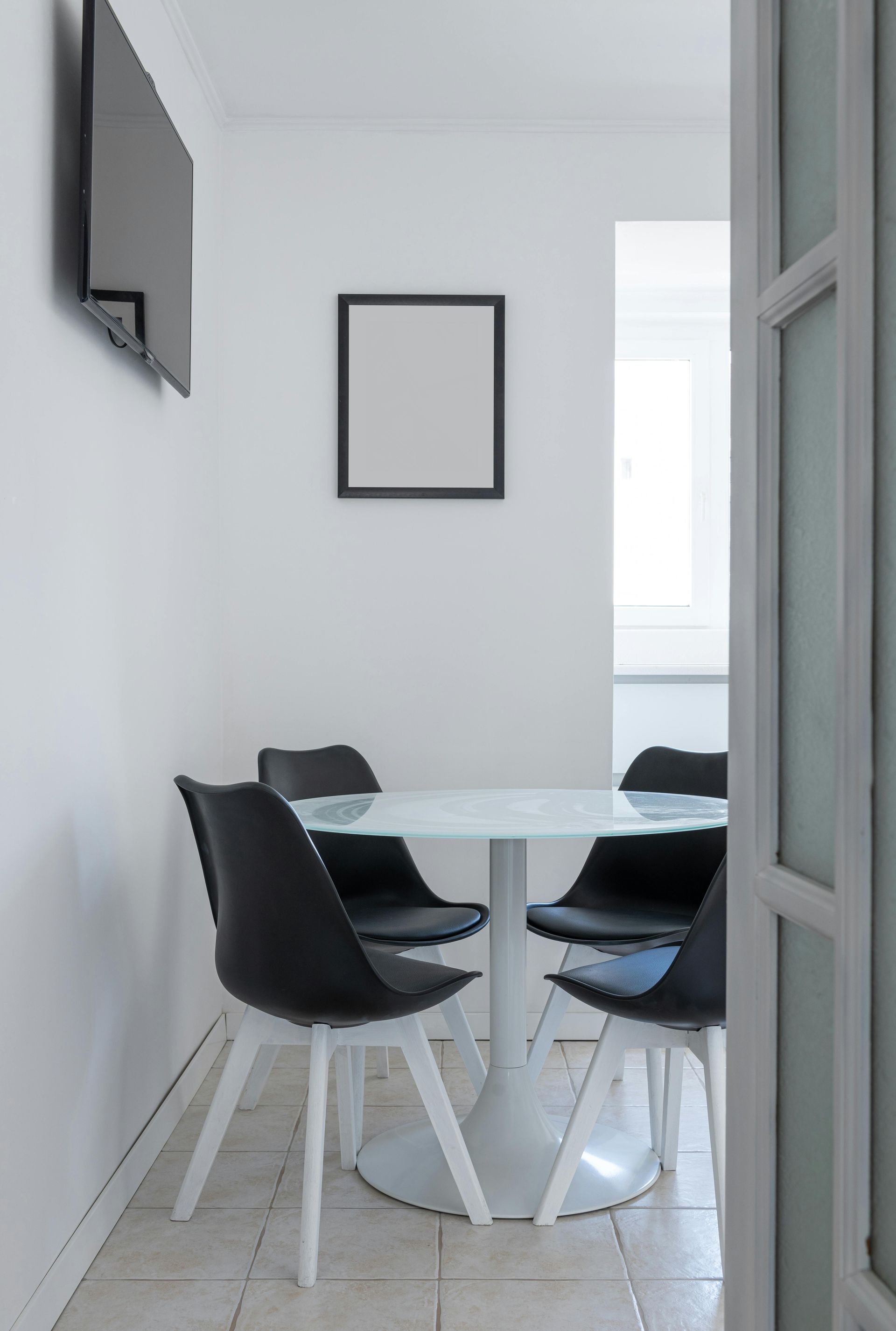 A dining room with a table and chairs and a flat screen tv on the wall.