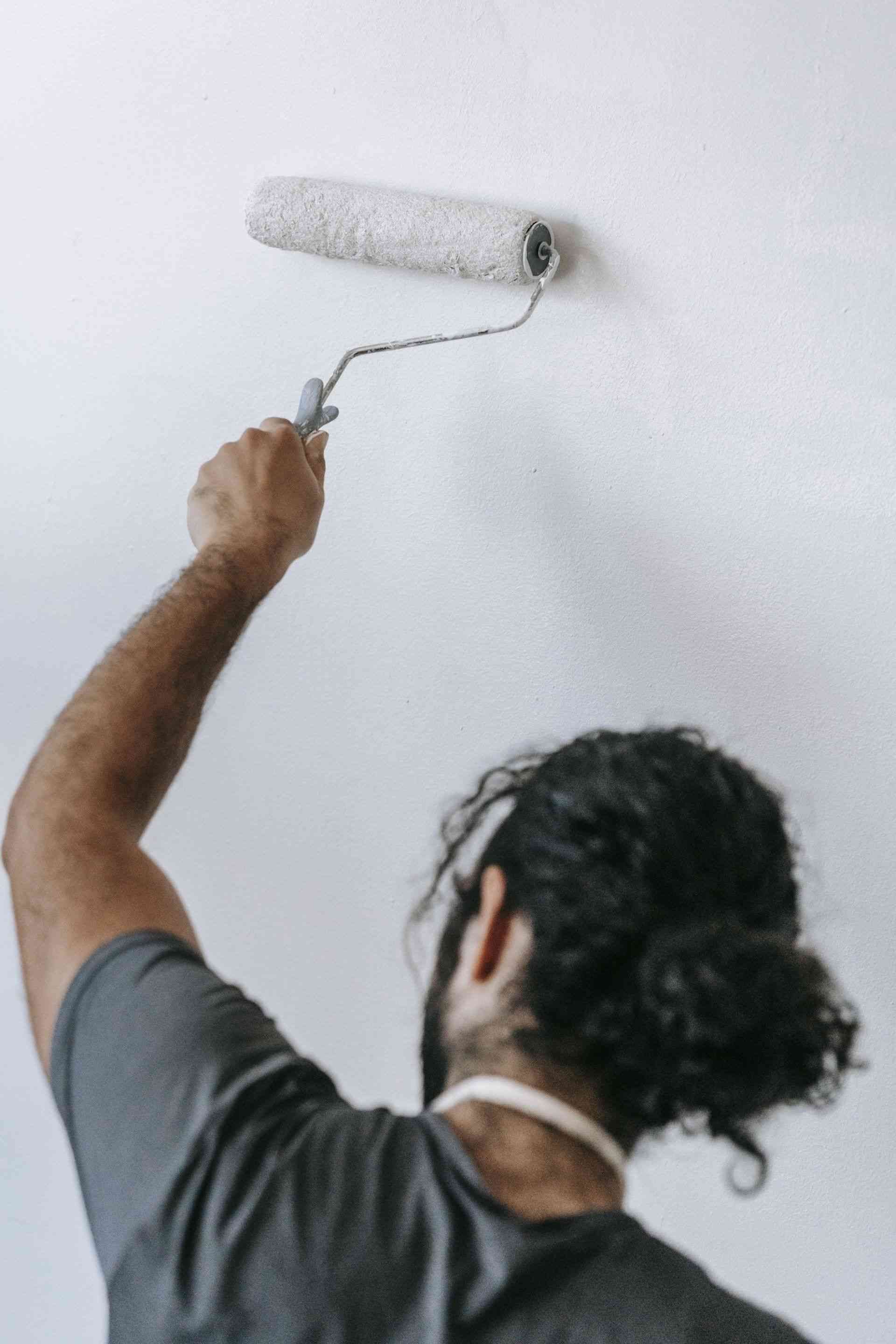 A man is painting a wall with a paint roller.