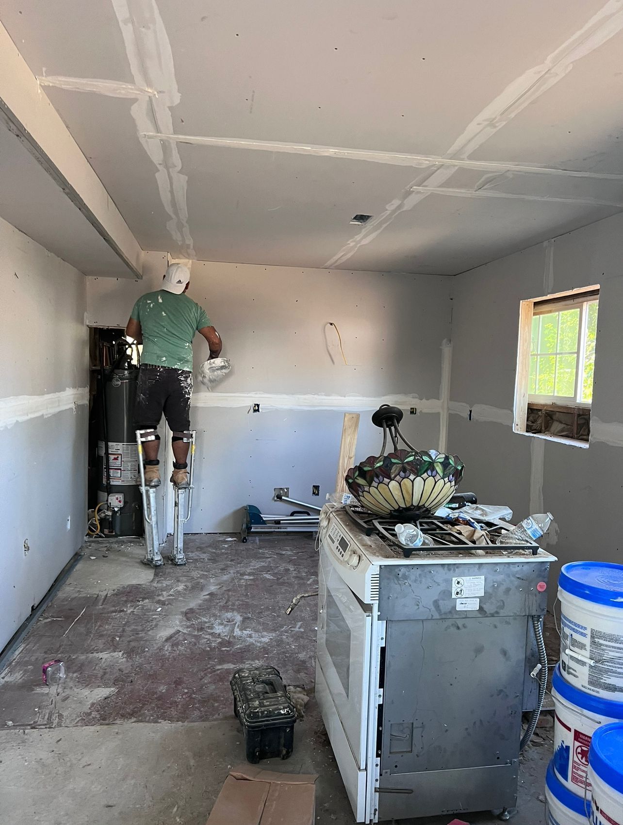 A man is painting the ceiling of a room in a garage.