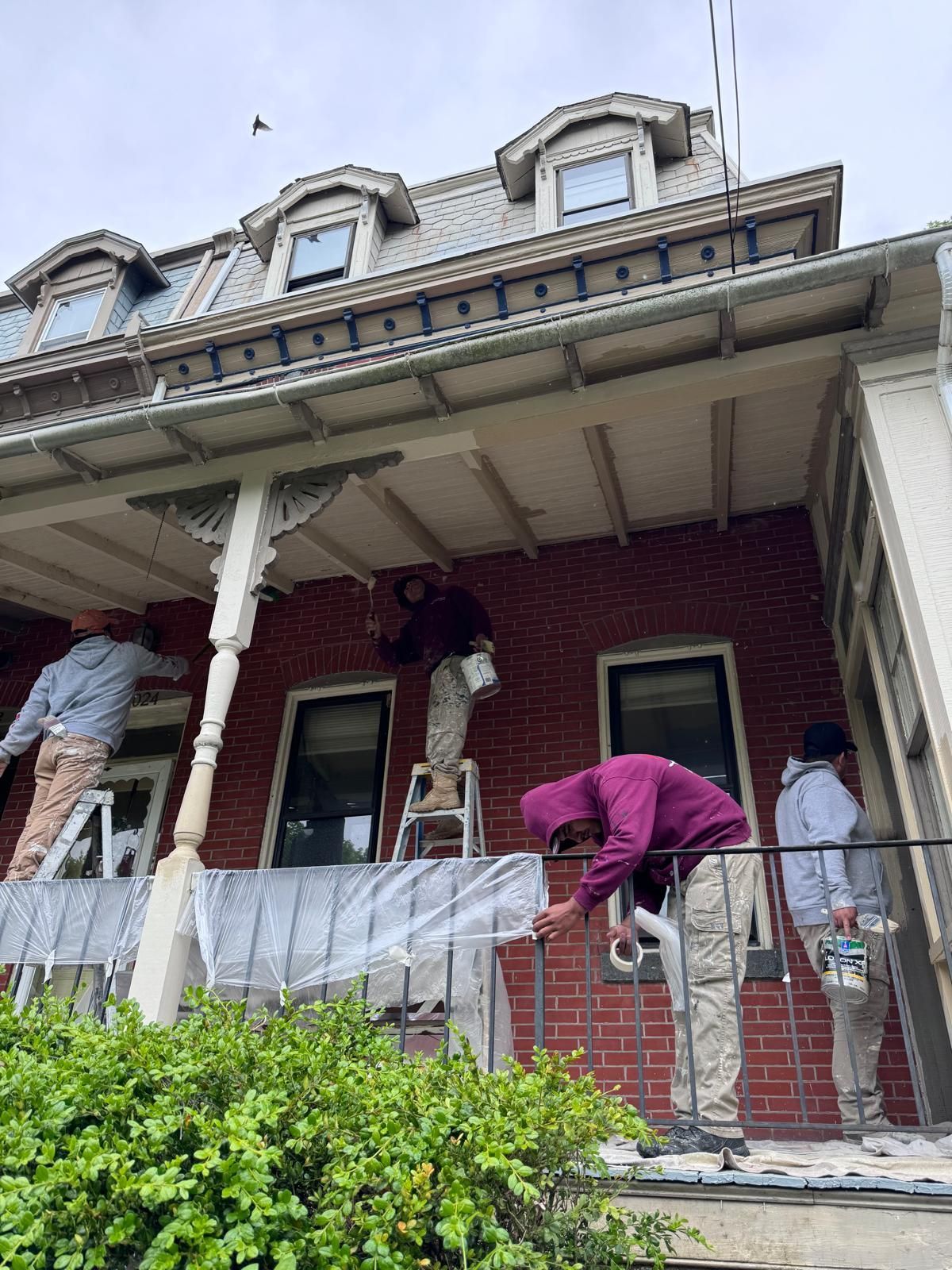 A group of people are painting a brick house.