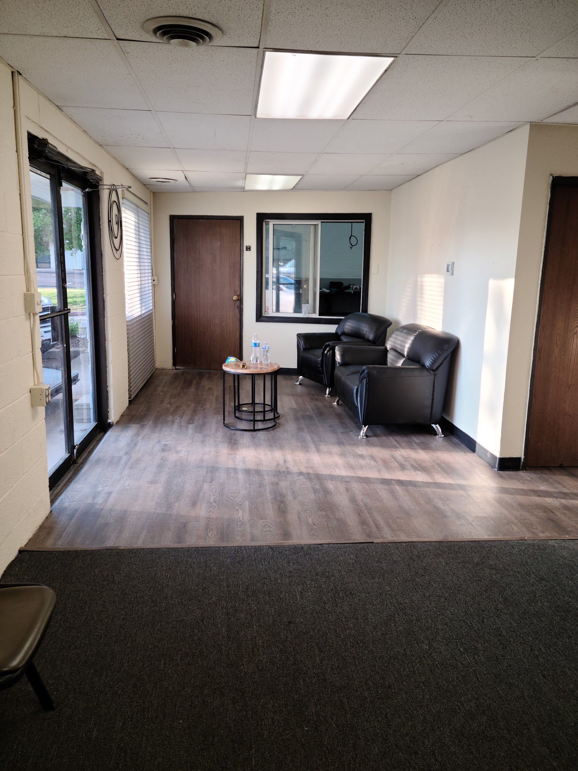Interior waiting area with dark leather sofa, window, and wood-look flooring. | Lenon's Tire & Auto Repair