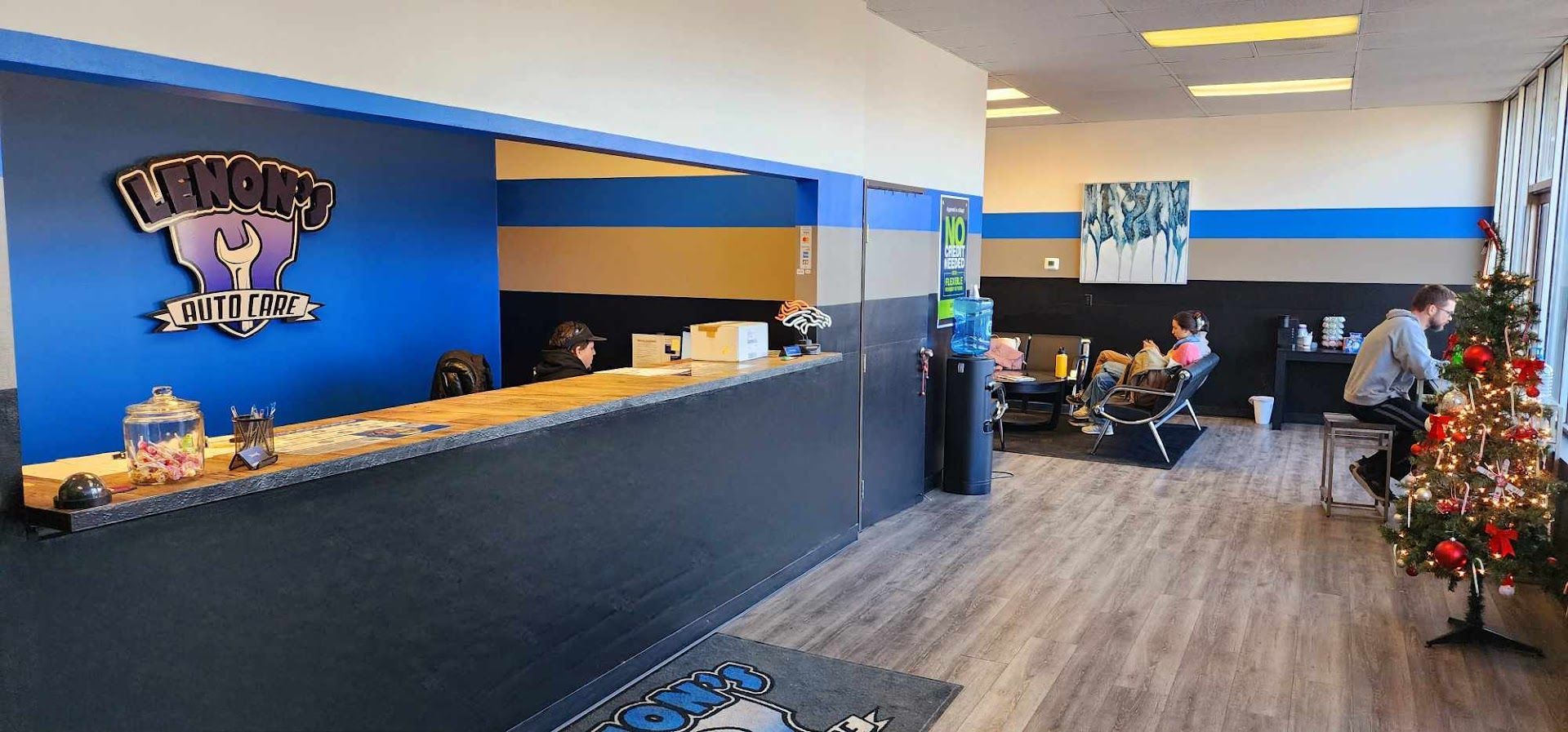 Gym reception area with a blue wall, logo, desk, and a Christmas tree. | Lenon's Tire & Auto Repair