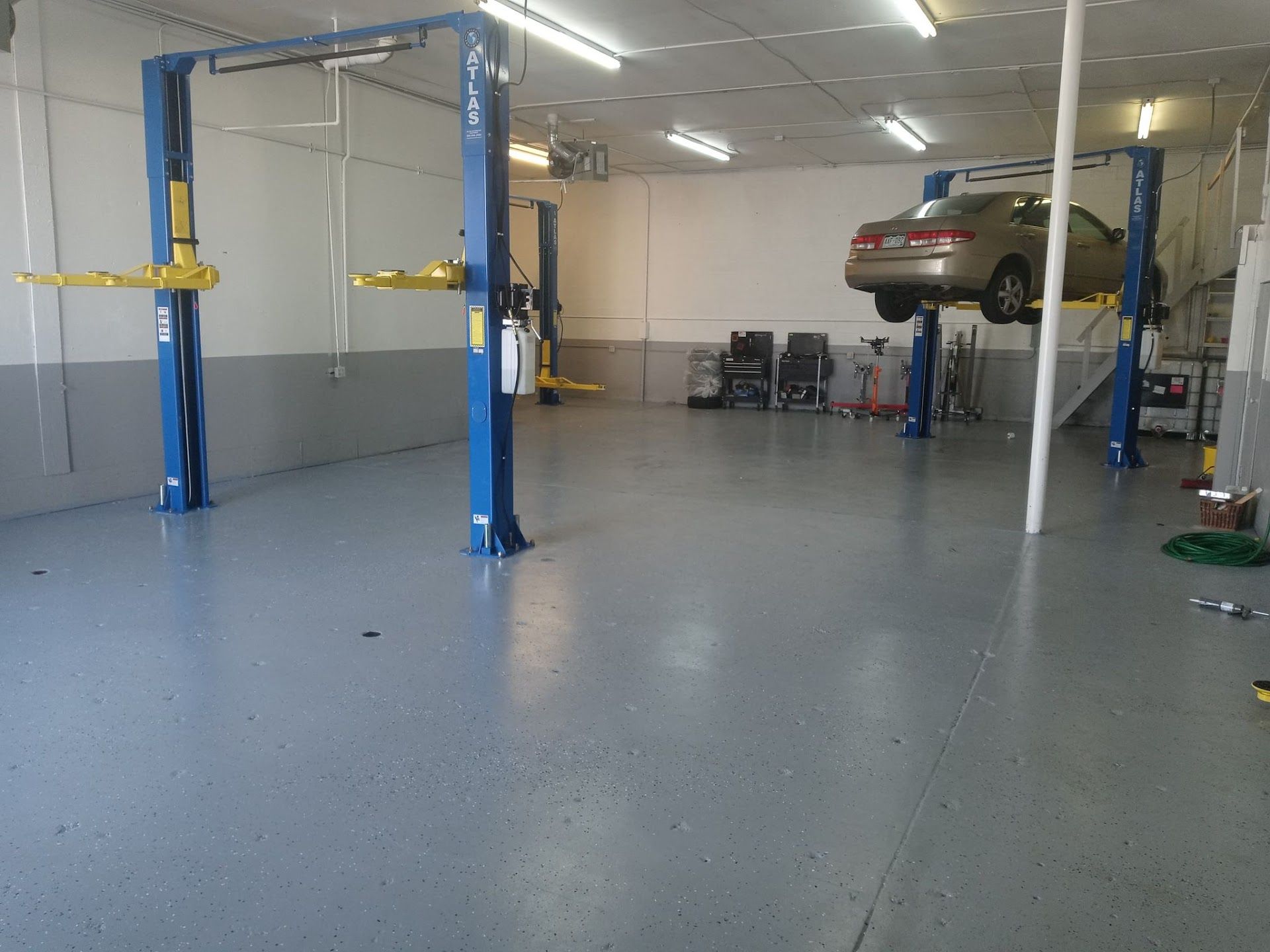 Car in a repair shop lifted on a hydraulic lift. Blue lifts and gray floor. | Lenon's Tire & Auto Repair