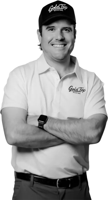 A man wearing a hat and a polo shirt is standing with his arms crossed.