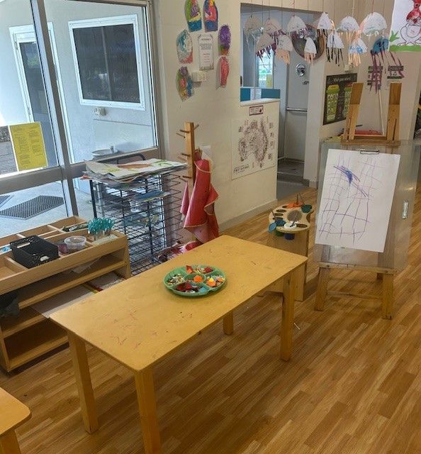 A Woman is Helping Two Little Girls Draw at a Table — Birralee Child Care Centre Assn Inc In Mackay, QLD