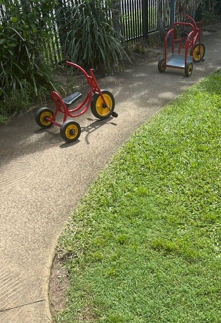 Two Red Trikes Parked by Grass — Birralee Child Care Centre Assn Inc In Mackay, QLD