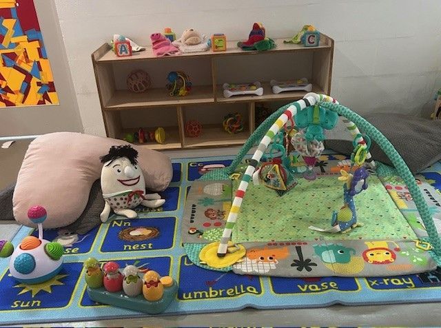 A Woman and Two Children Are Sitting at a Table Painting — Birralee Child Care Centre Assn Inc In Mackay, QLD