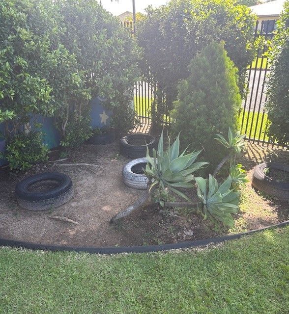 A Little Girl is Sitting at a Table Drawing With a Pencil — Birralee Child Care Centre Assn Inc In Mackay, QLD