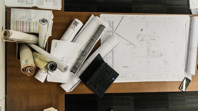 rolled up architectural drawings and computer sitting on office desk