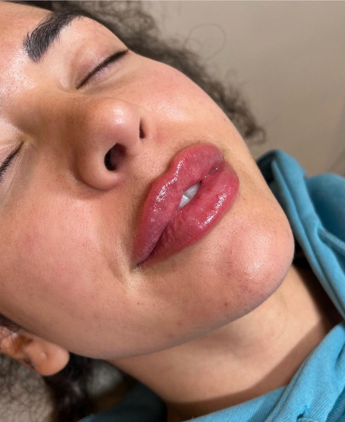 A Woman With Red Lips is Laying Down With Her Eyes Closed — Doll Empire Clinic in Mermaid Beach, QLD