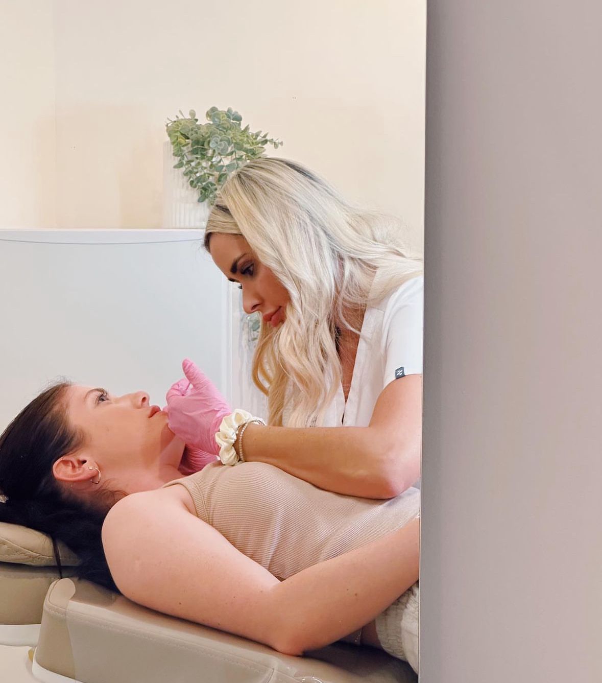 A Woman is Laying on a Bed Getting a Facial Treatment From a Nurse — Doll Empire Clinic in Mermaid Beach, QLD