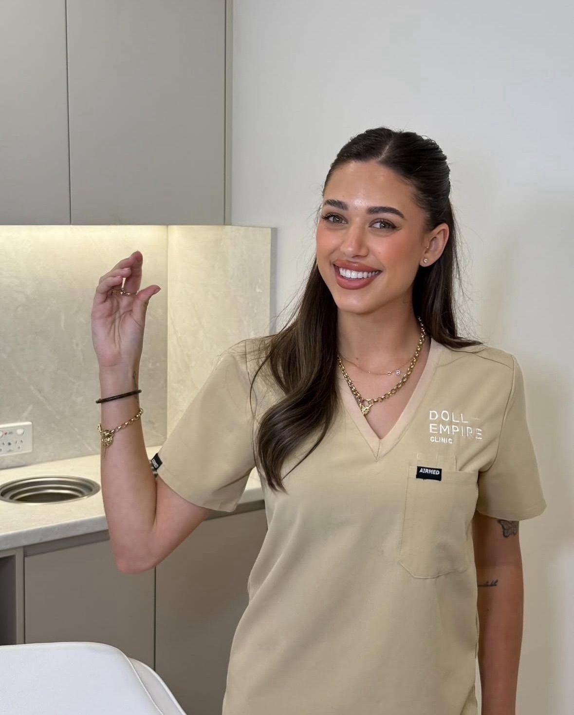 A Woman is Standing in Front of a Sign That Says Empire Clinic — Doll Empire Clinic in Mermaid Beach, QLD