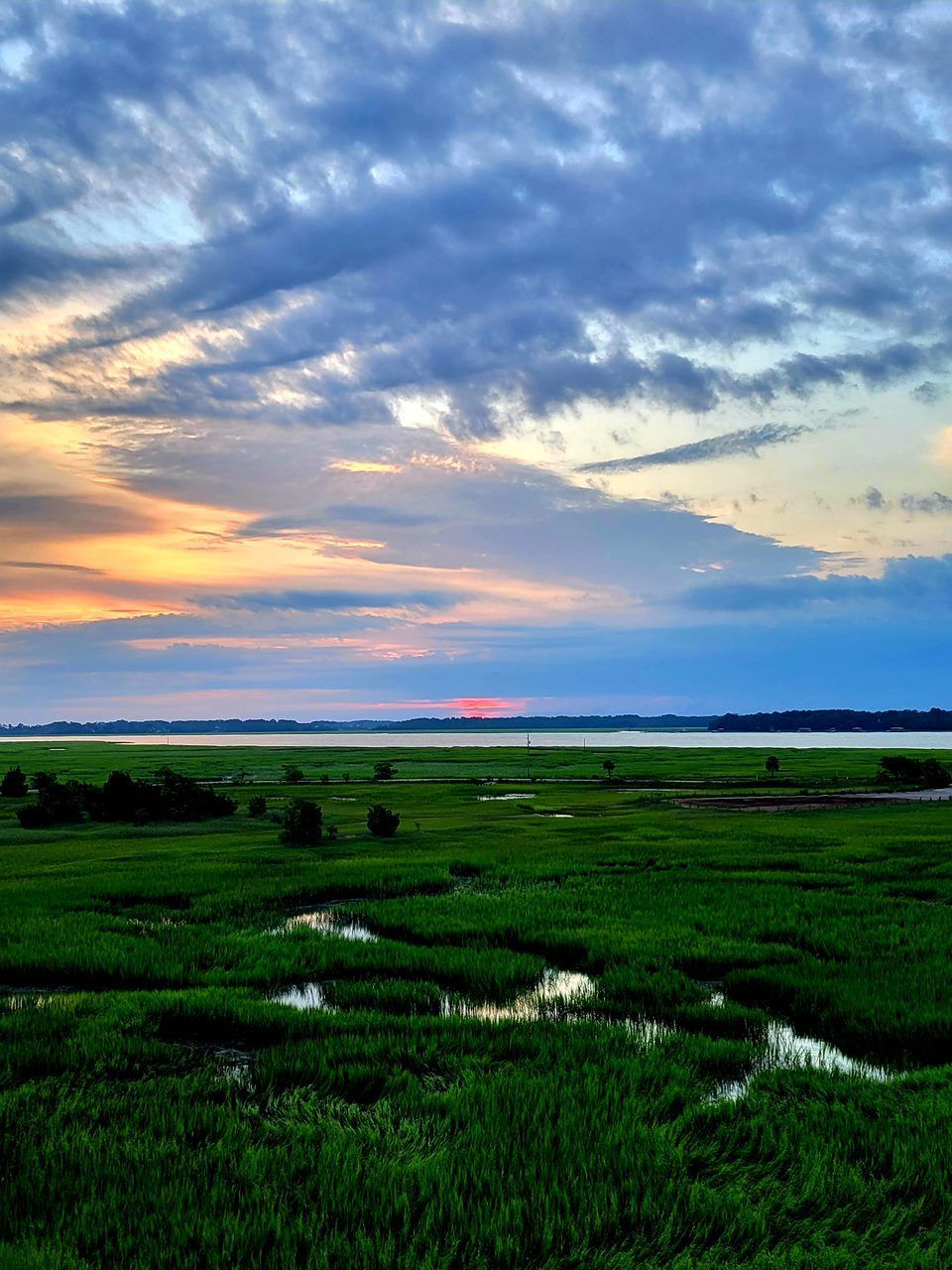 Beaufort SC Green marsh at sunset, under a cloudy sky.