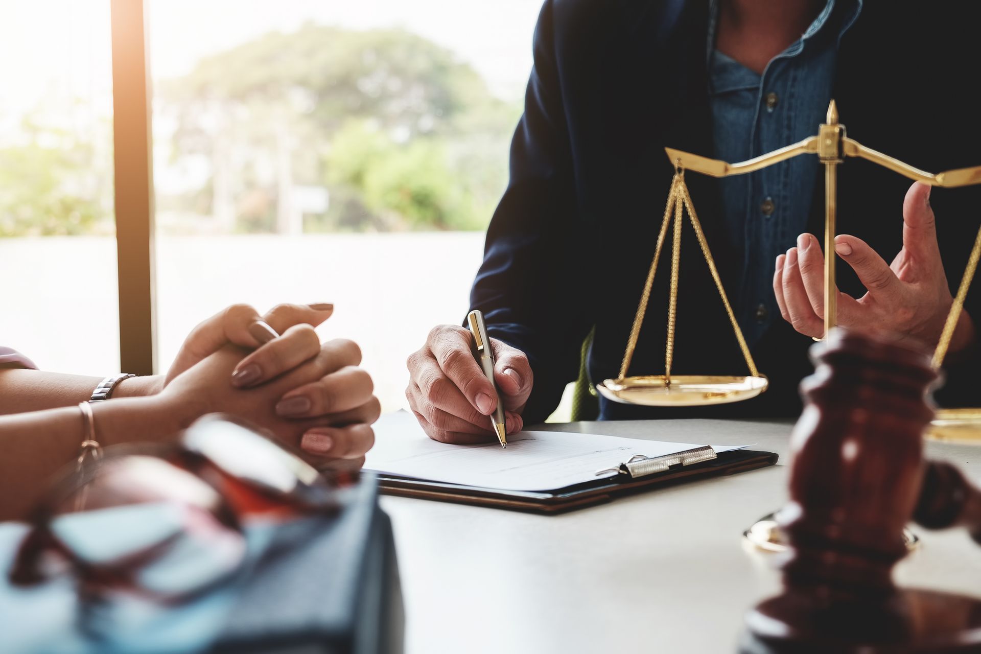 Lawyer reviewing documents with a client, with a balance scale and gavel on the desk.