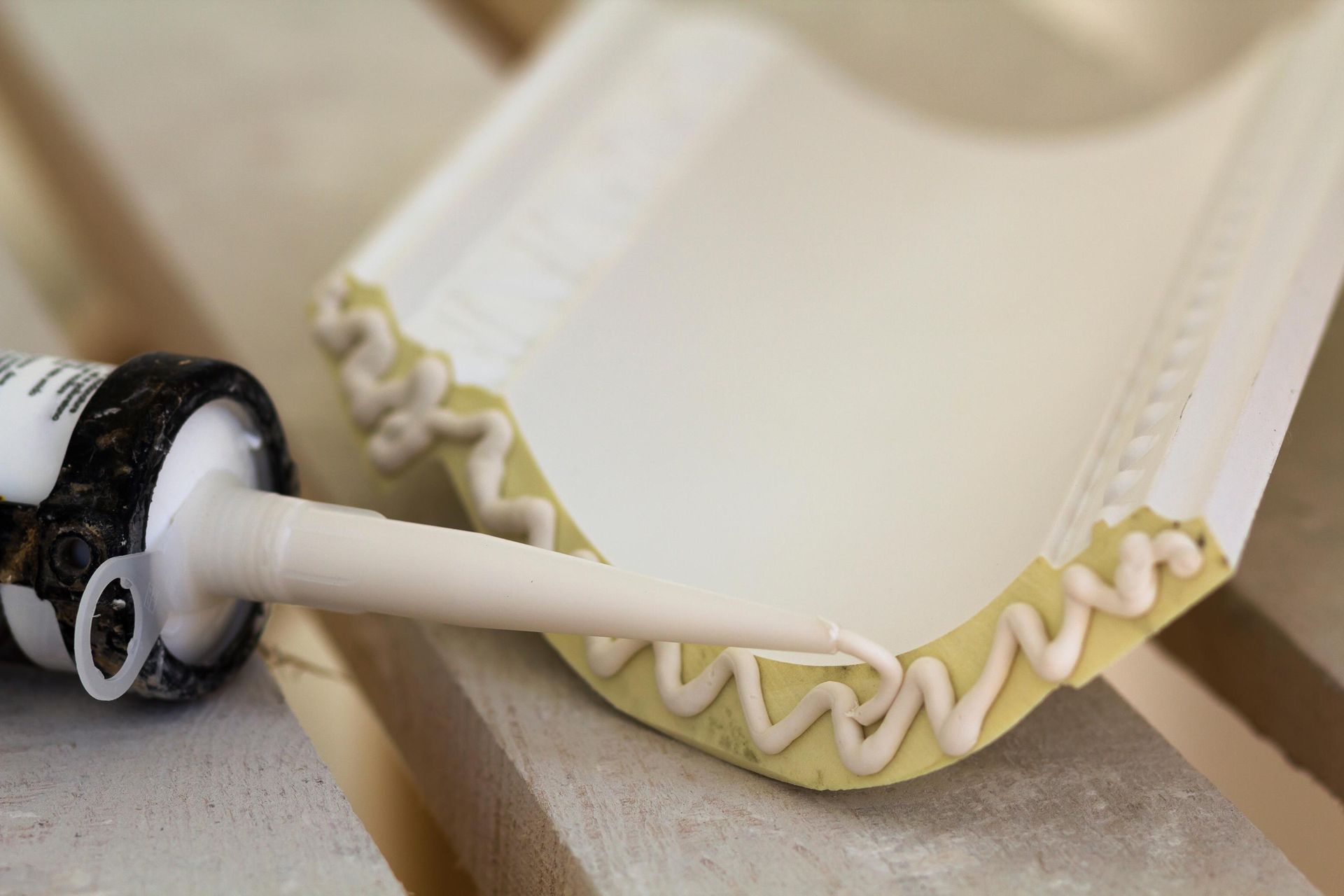 A bottle of glue is being applied to a piece of wood.