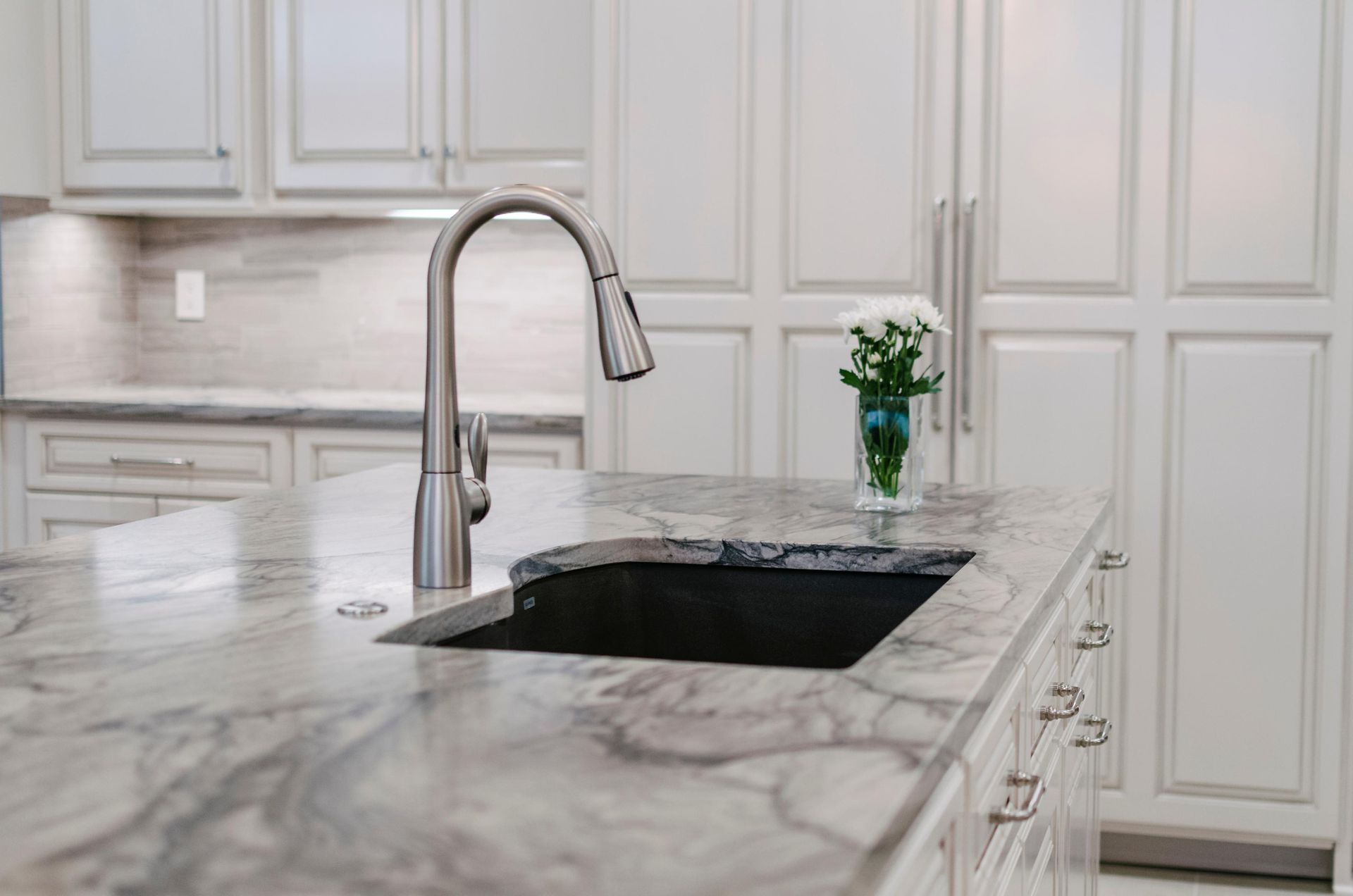 A kitchen with a sink and a vase of flowers on the counter.