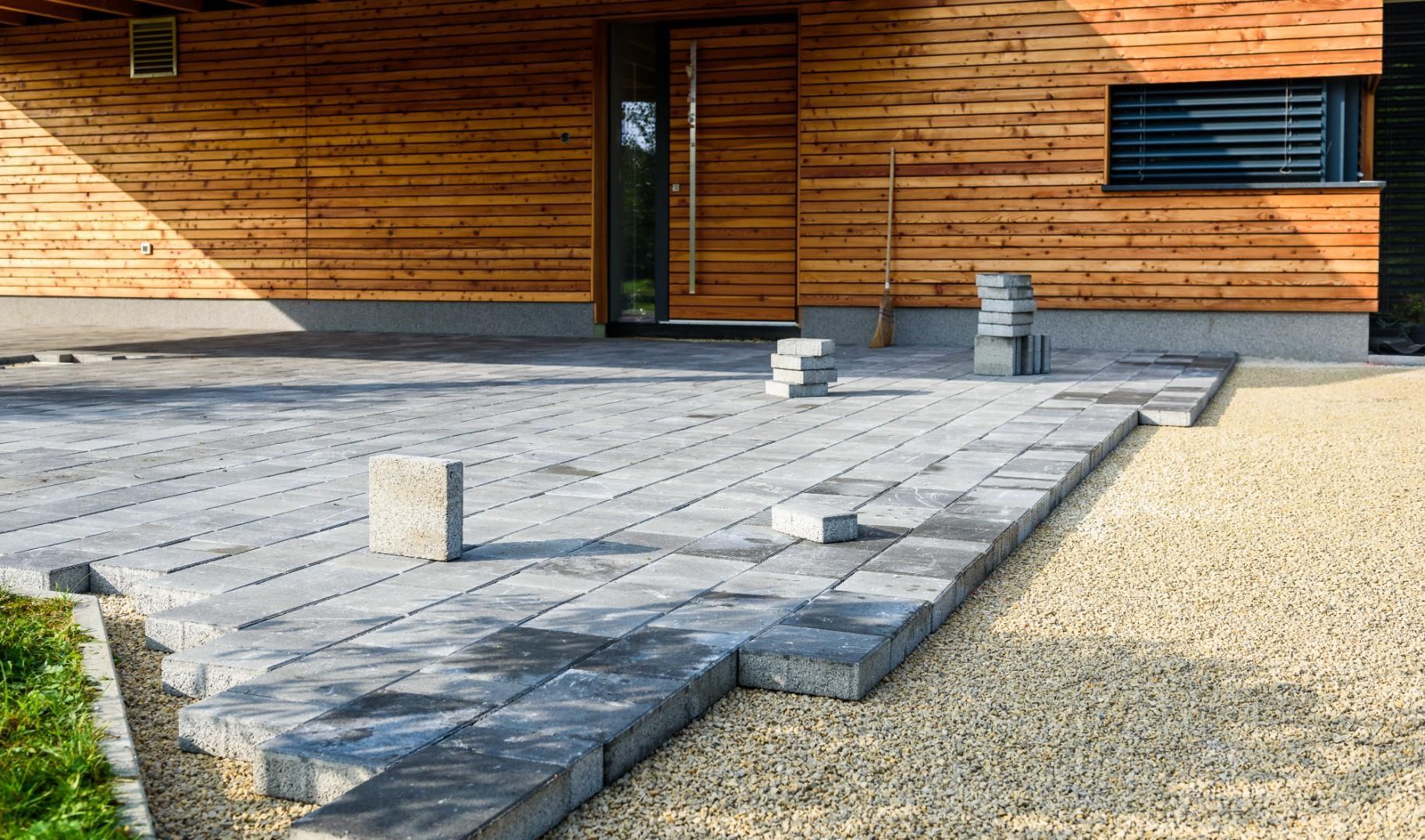 A driveway is being built in front of a wooden house.