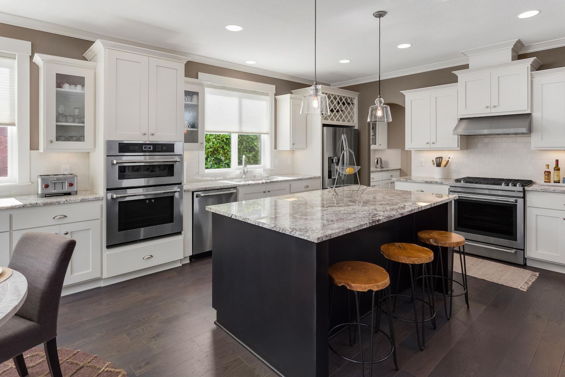 A kitchen with white cabinets, granite counter tops, stainless steel appliances ,and a large island.