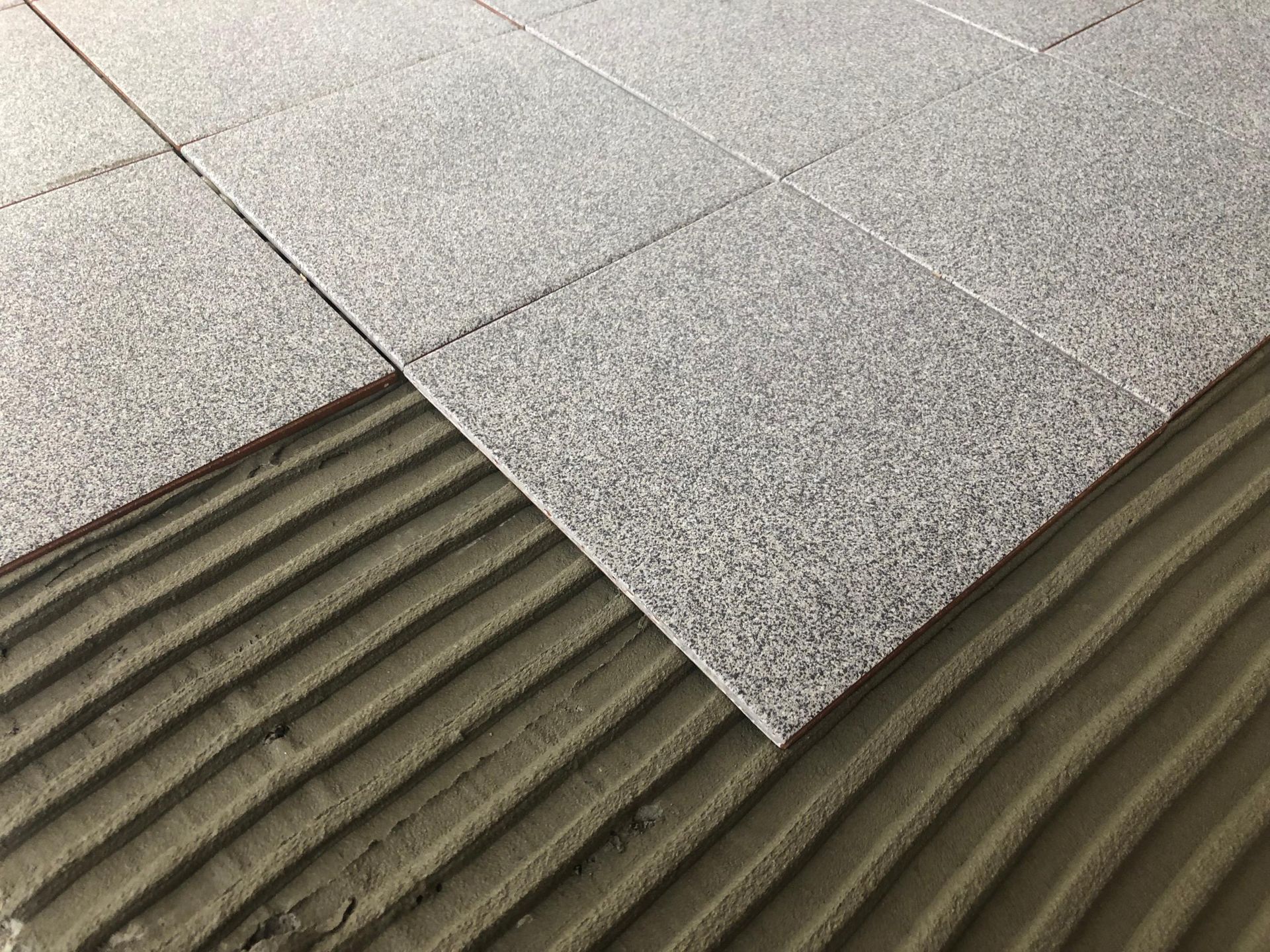 A tile is being installed on a cement floor.