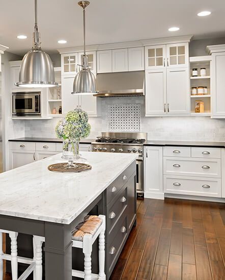 A kitchen with white cabinets and a large island in the middle.