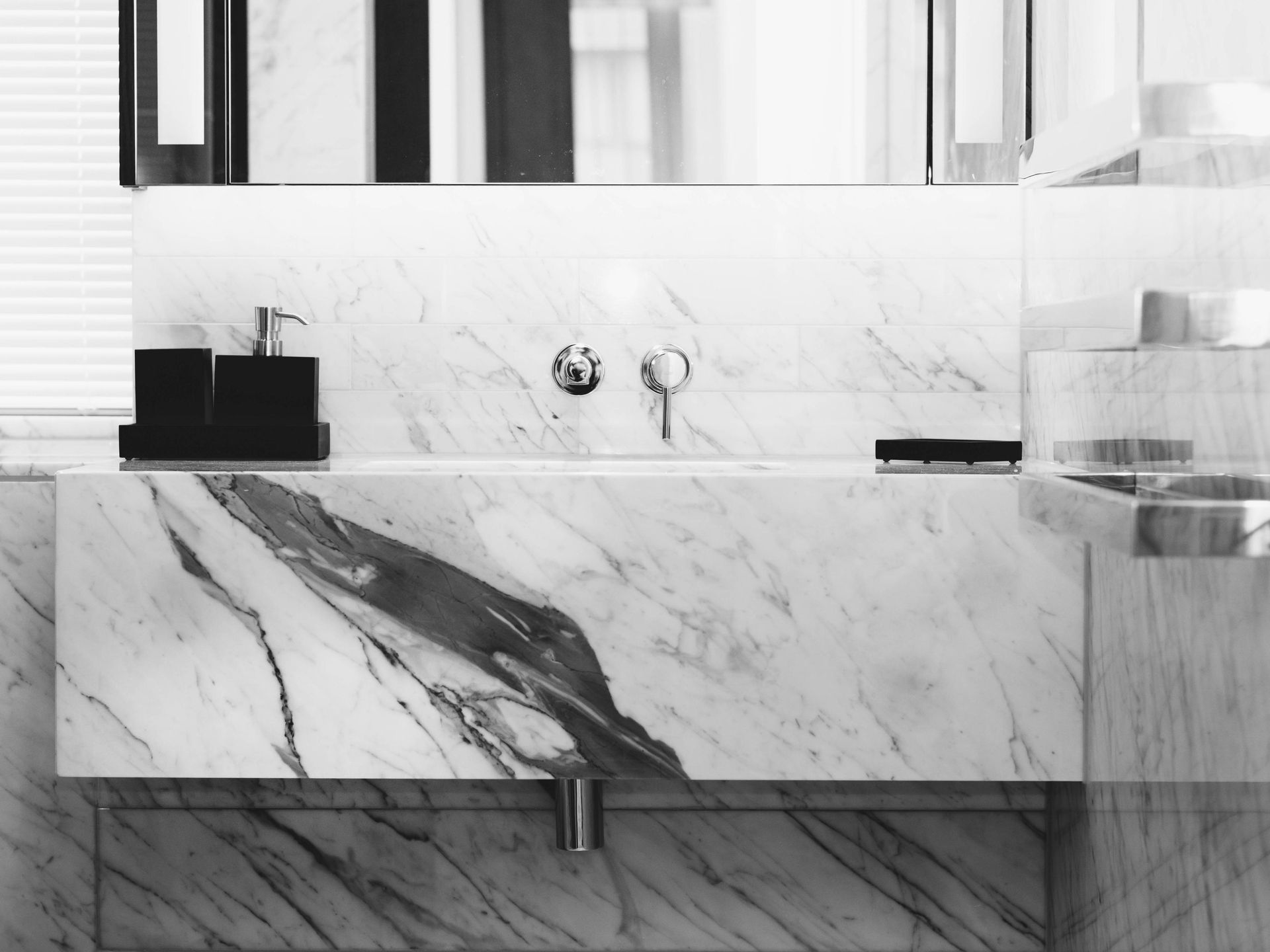 A black and white photo of a bathroom with a marble sink.